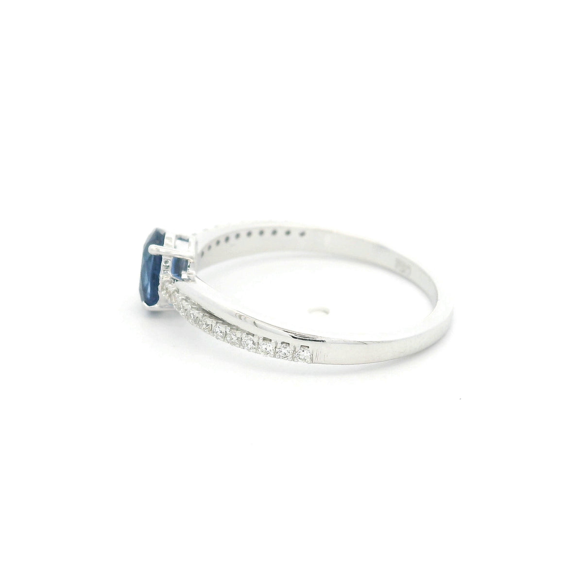 Oval blue sapphire ring with diamond-set shoulders in polished 18K white gold, featuring a four-prong centre gemstone setting.