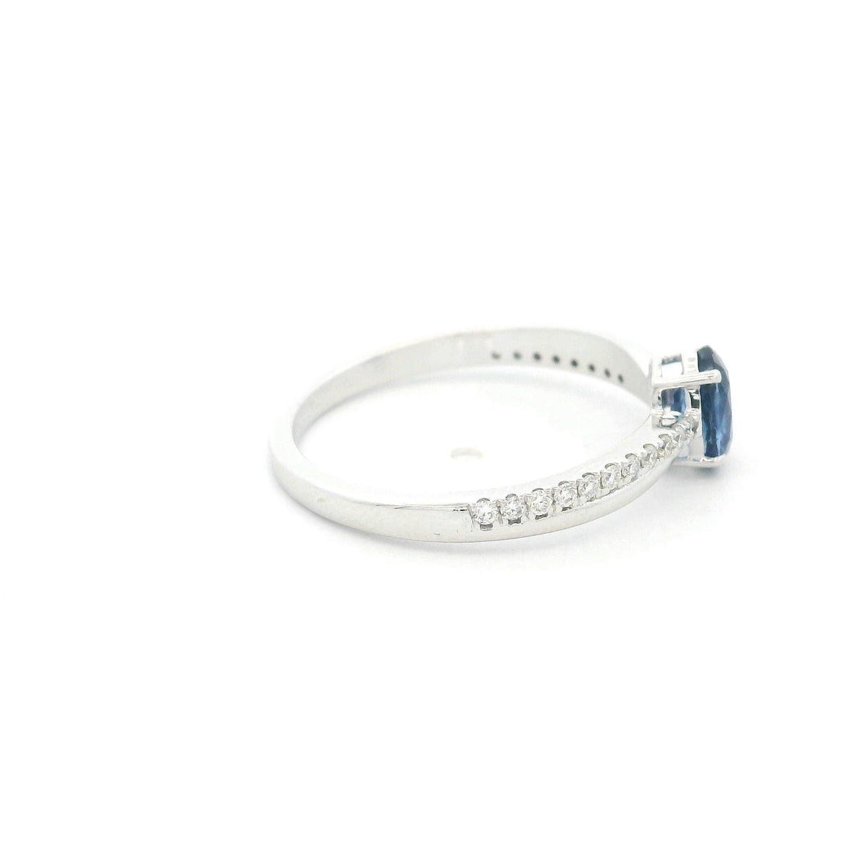 Oval blue sapphire ring with diamond-set shoulders in polished 18K white gold, featuring a four-prong centre gemstone setting.