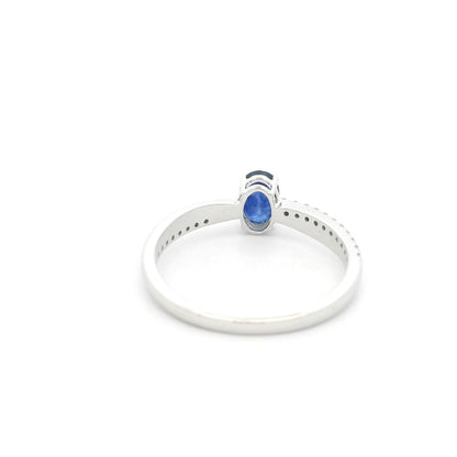 Oval blue sapphire ring with diamond-set shoulders in polished 18K white gold, featuring a four-prong centre gemstone setting.