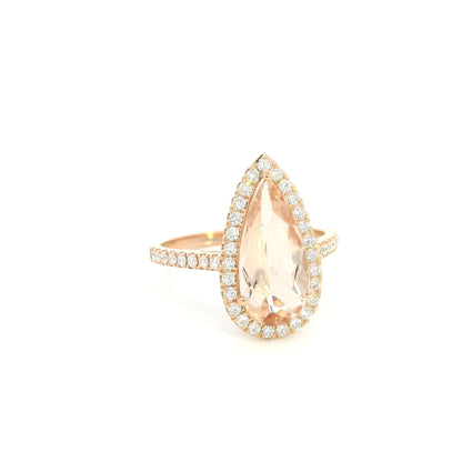 Pear shaped morganite ring in 18K rose gold with a 2.58 carat pink gemstone, round diamond halo and pavé diamond band.