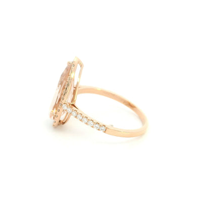 Pear shaped morganite ring in 18K rose gold with a 2.58 carat pink gemstone, round diamond halo and pavé diamond band.