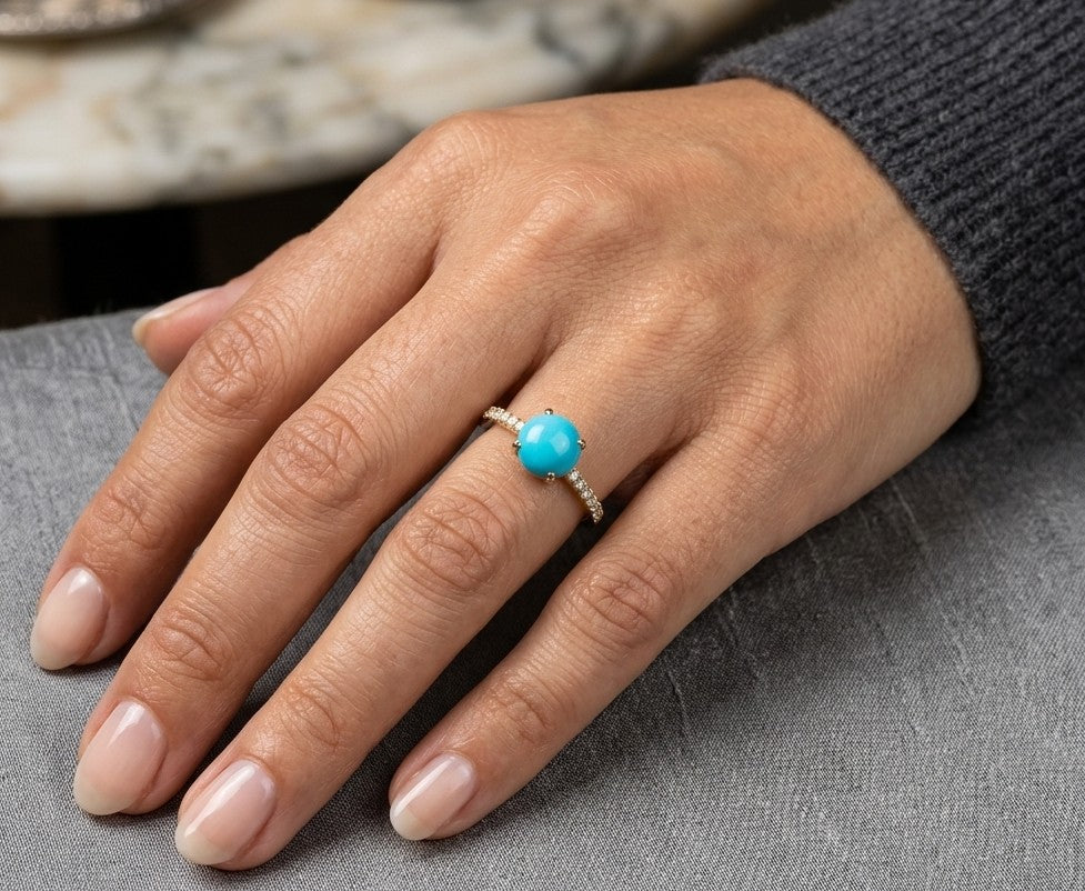 18K yellow gold turquoise and diamond ring featuring a round cabochon turquoise gemstone in a four-prong setting with round diamonds along the band.