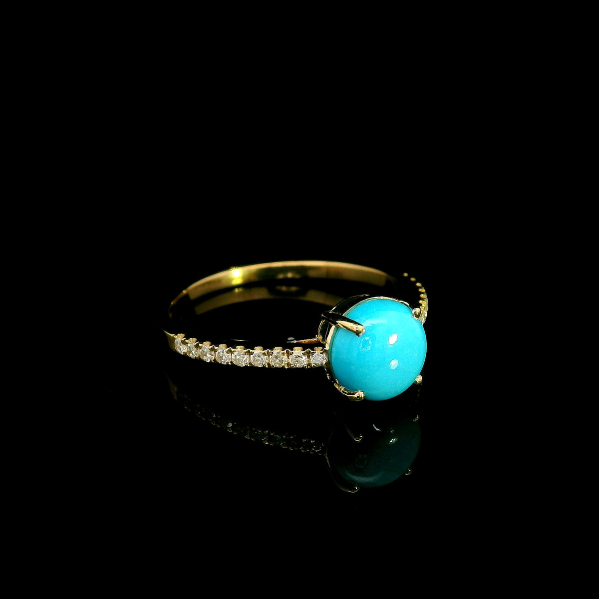 18K yellow gold turquoise and diamond ring featuring a round cabochon turquoise gemstone in a four-prong setting with round diamonds along the band.