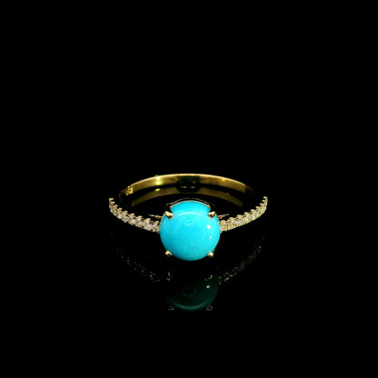 18K yellow gold turquoise and diamond ring featuring a round cabochon turquoise gemstone in a four-prong setting with round diamonds along the band.