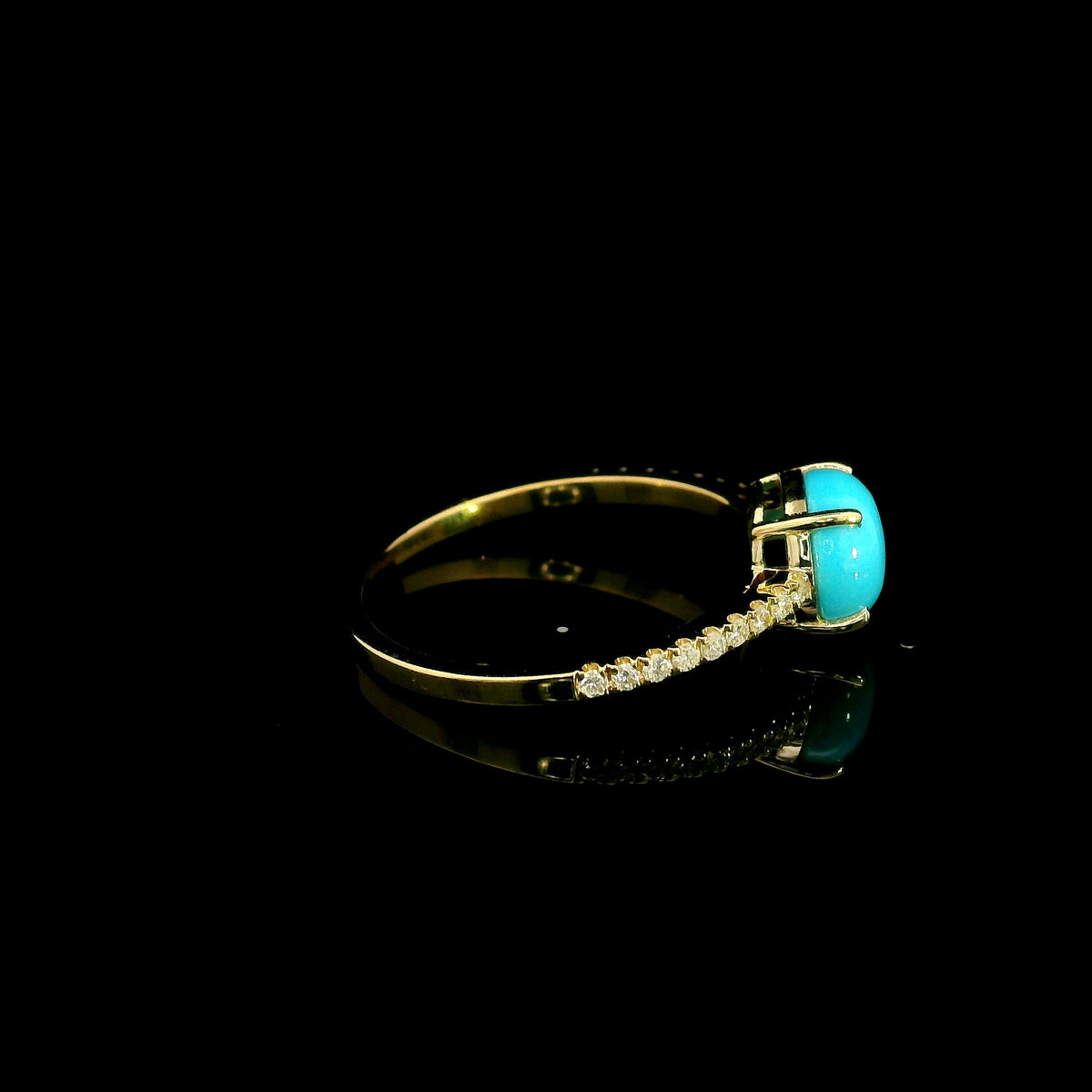 18K yellow gold turquoise and diamond ring featuring a round cabochon turquoise gemstone in a four-prong setting with round diamonds along the band.