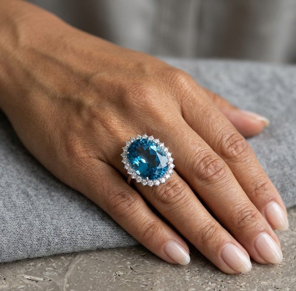 Swiss Blue Topaz halo ring in 18K white gold with an oval blue gemstone surrounded by round diamonds.
