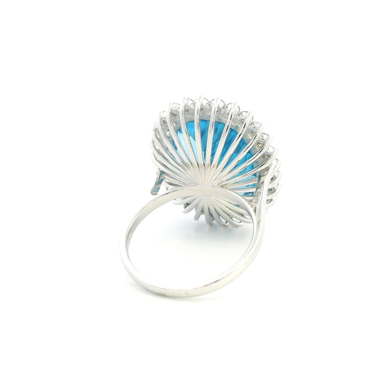 Swiss Blue Topaz halo ring in 18K white gold with an oval blue gemstone surrounded by round diamonds.