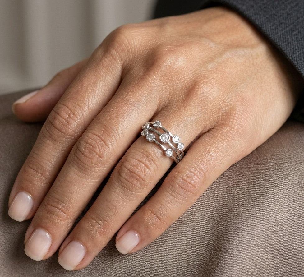 Diamond bezel set multi-row ring in 18K white gold featuring asymmetrically arranged round diamonds across polished open bands.