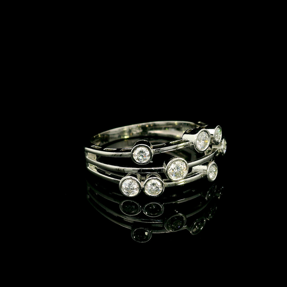 Diamond bezel set multi-row ring in 18K white gold featuring asymmetrically arranged round diamonds across polished open bands.