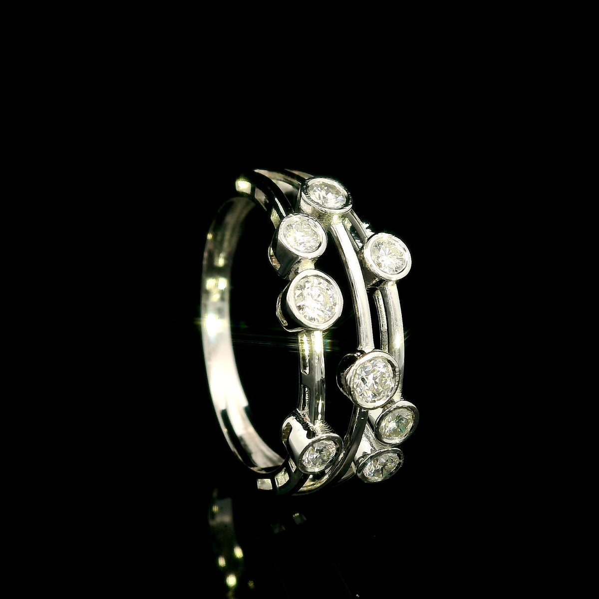 Diamond bezel set multi-row ring in 18K white gold featuring asymmetrically arranged round diamonds across polished open bands.