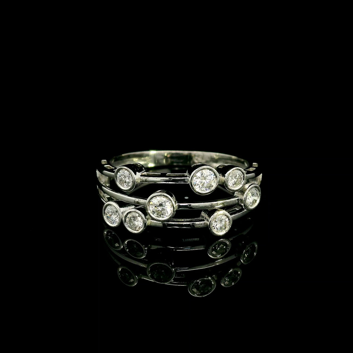 Diamond bezel set multi-row ring in 18K white gold featuring asymmetrically arranged round diamonds across polished open bands.