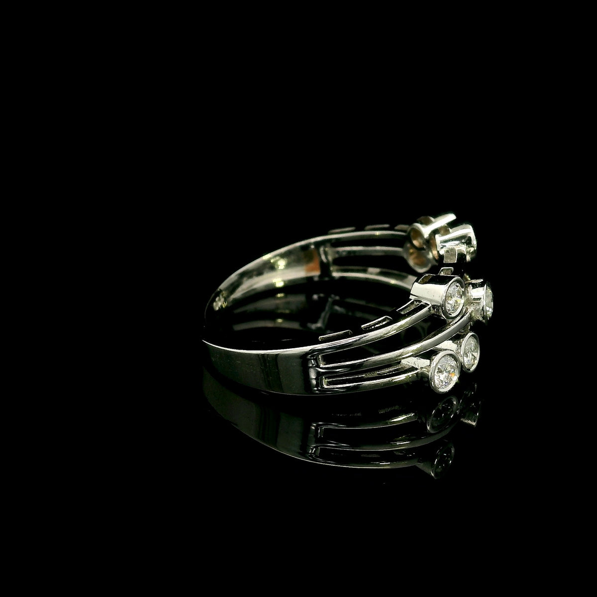 Diamond bezel set multi-row ring in 18K white gold featuring asymmetrically arranged round diamonds across polished open bands.