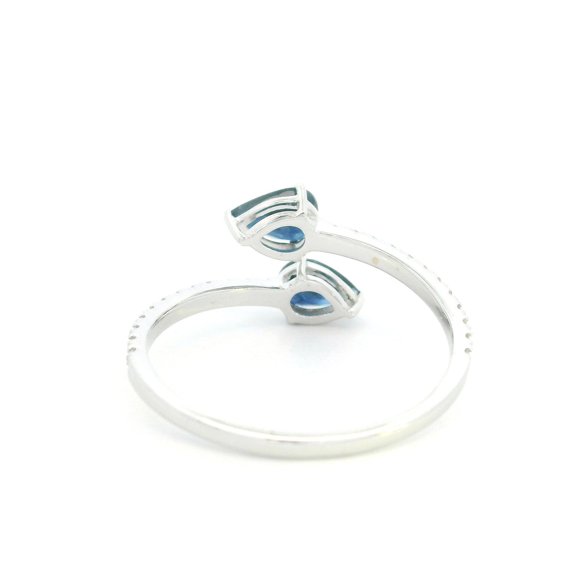 18K white gold blue sapphire Toi et Moi ring featuring two pear-shaped blue sapphires positioned in opposite directions with round diamonds along the open band.