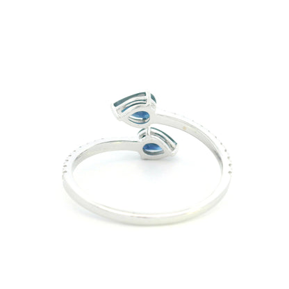 18K white gold blue sapphire Toi et Moi ring featuring two pear-shaped blue sapphires positioned in opposite directions with round diamonds along the open band.