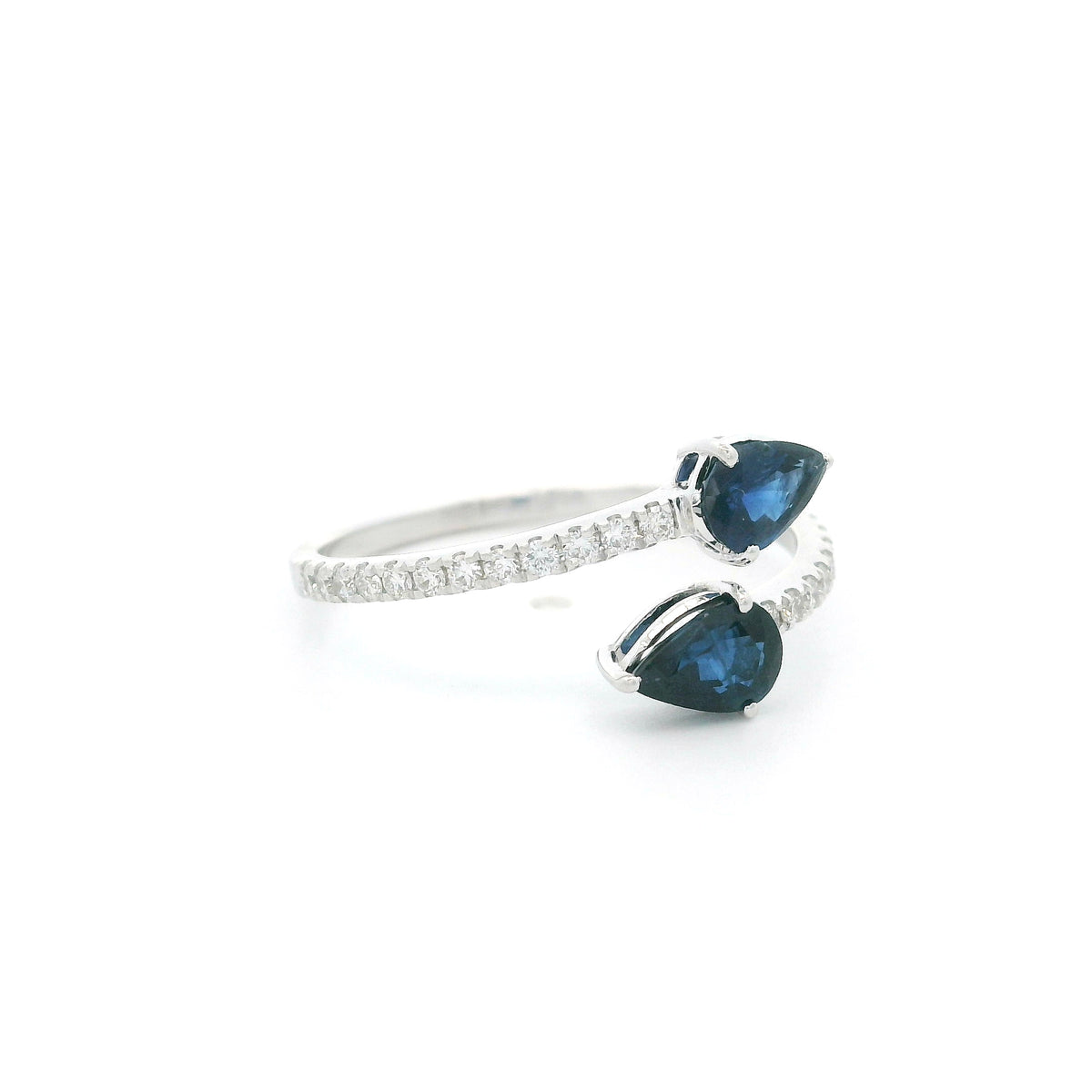 18K white gold blue sapphire Toi et Moi ring featuring two pear-shaped blue sapphires positioned in opposite directions with round diamonds along the open band.