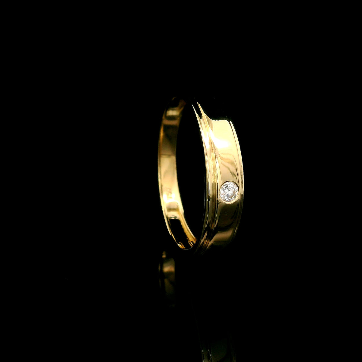 Men's 18K yellow gold band featuring a single round flush-set diamond, polished finish and fine grooved detailing.