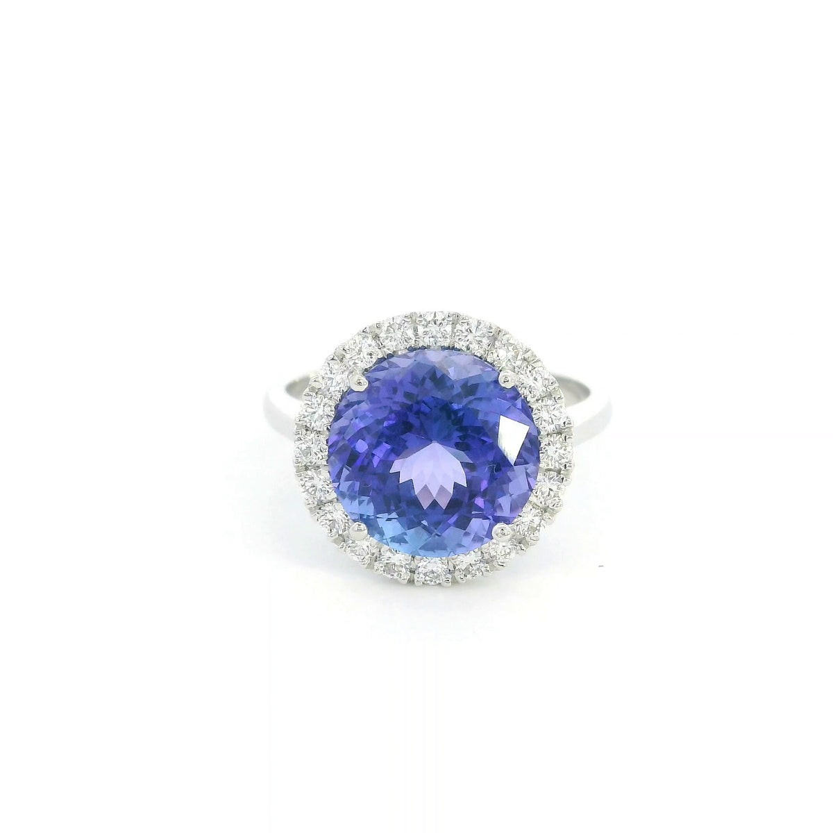 Round tanzanite and diamond halo ring in 18K white gold featuring a 5.97 carat violet-blue tanzanite surrounded by round diamonds on a polished band.