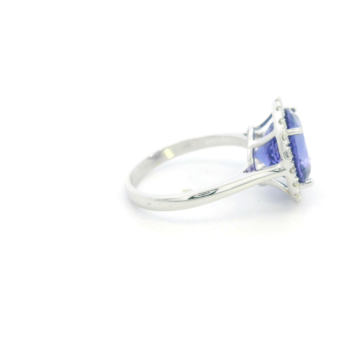 Round tanzanite and diamond halo ring in 18K white gold featuring a 5.97 carat violet-blue tanzanite surrounded by round diamonds on a polished band.