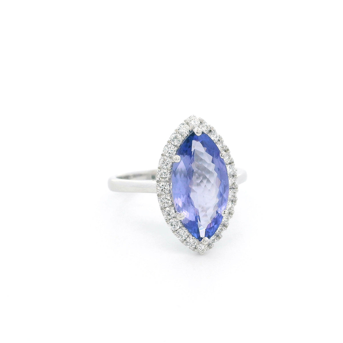 Marquise tanzanite and diamond halo ring in 18K white gold featuring a blue-violet gemstone surrounded by round diamonds.
