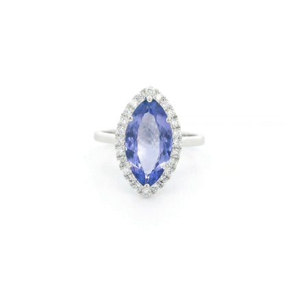 Marquise tanzanite and diamond halo ring in 18K white gold featuring a blue-violet gemstone surrounded by round diamonds.
