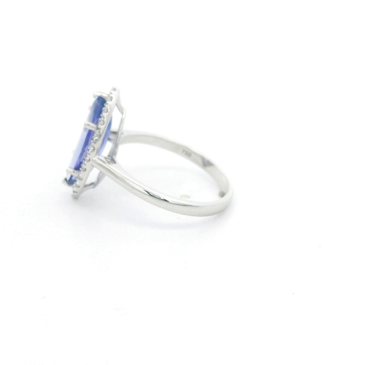 Marquise tanzanite and diamond halo ring in 18K white gold featuring a blue-violet gemstone surrounded by round diamonds.