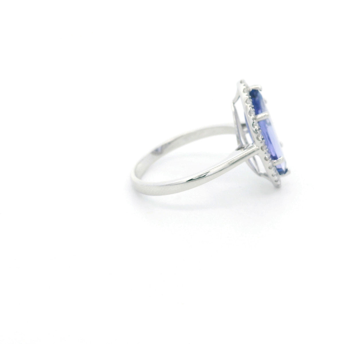 Marquise tanzanite and diamond halo ring in 18K white gold featuring a blue-violet gemstone surrounded by round diamonds.