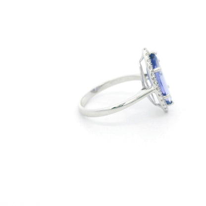 Marquise tanzanite and diamond halo ring in 18K white gold featuring a blue-violet gemstone surrounded by round diamonds.