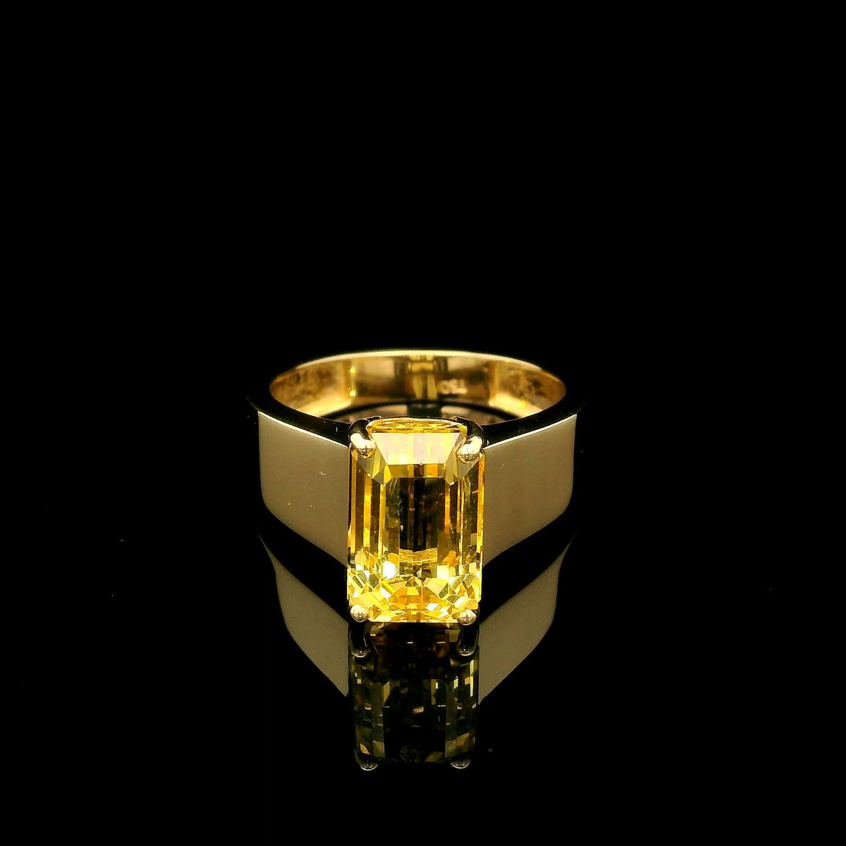 Men's yellow beryl ring in 18K yellow gold featuring a rectangular emerald-cut gemstone in a four-prong setting and a wide gold band.