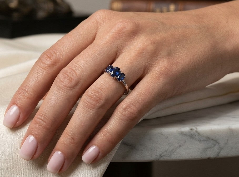 18K white gold ring featuring three oval blue sapphires, with a larger centre gemstone and two smaller side stones on a slim polished band.