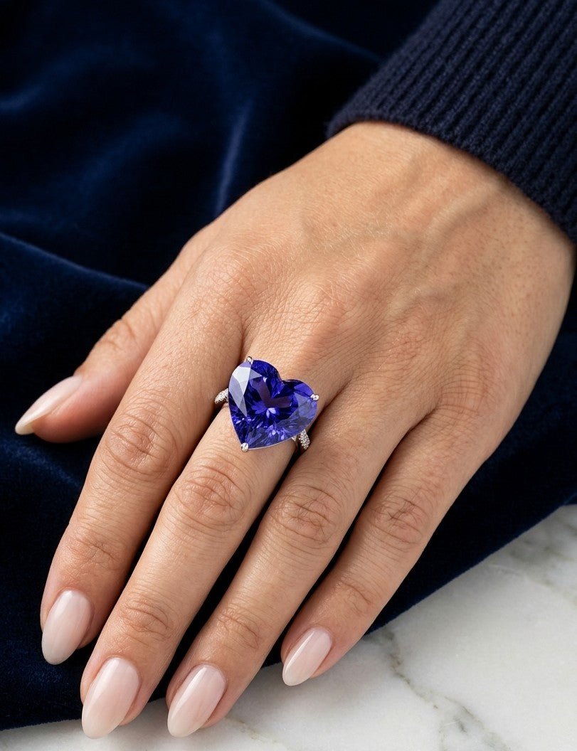 Heart shaped tanzanite ring in 18K white gold featuring a 25.18 carat blue-violet gemstone and diamond-set shoulders.