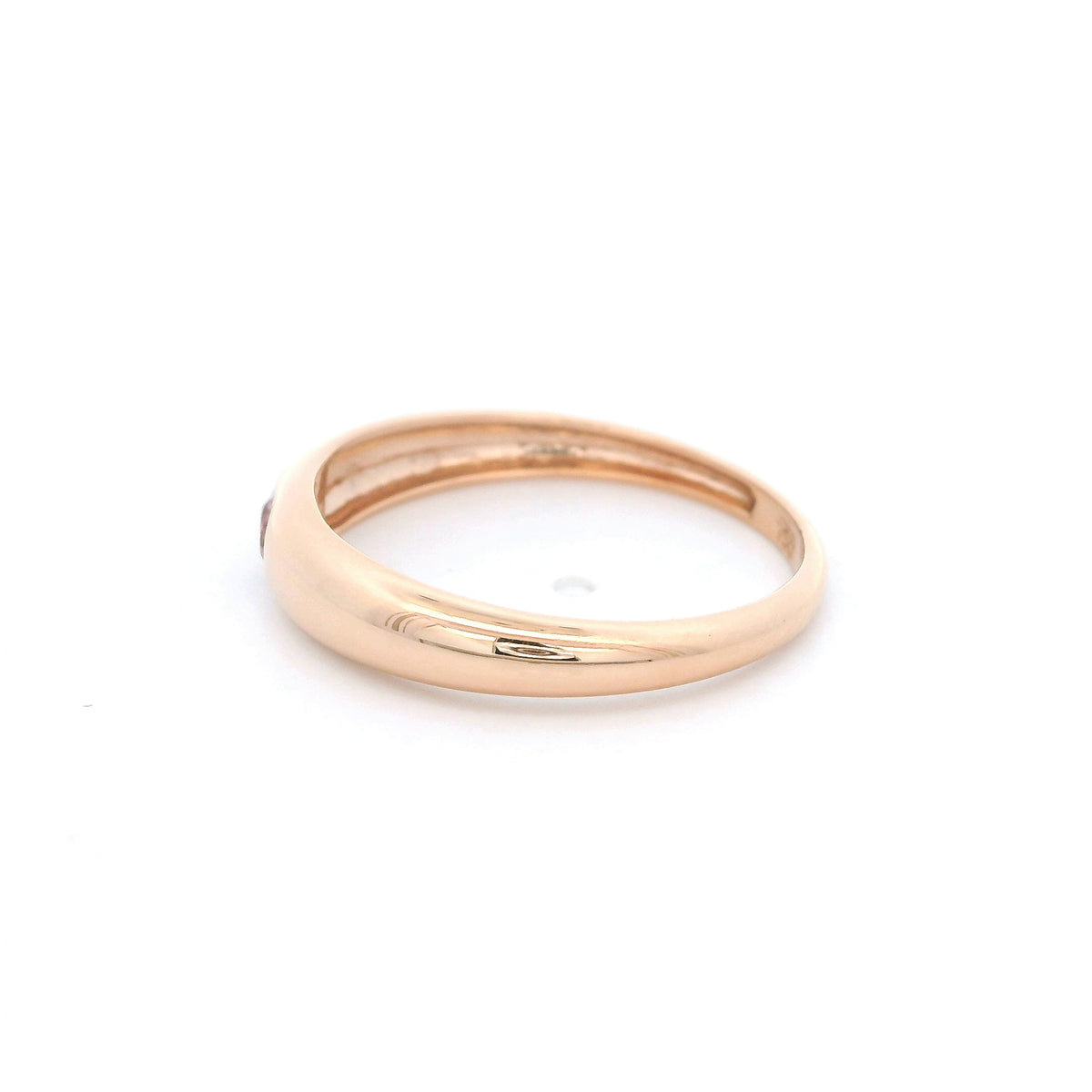 Pink tourmaline ring in 18K rose gold featuring a small round pink gemstone set into a smooth, polished, rounded gold band.
