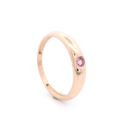 Pink tourmaline ring in 18K rose gold featuring a small round pink gemstone set into a smooth, polished, rounded gold band.