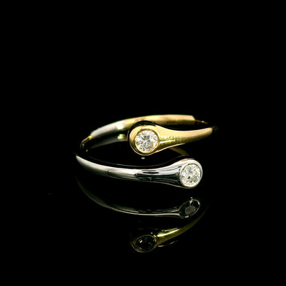 18K white and yellow gold bypass ring with two round diamonds in bezel settings at the ends of curved, overlapping bands.