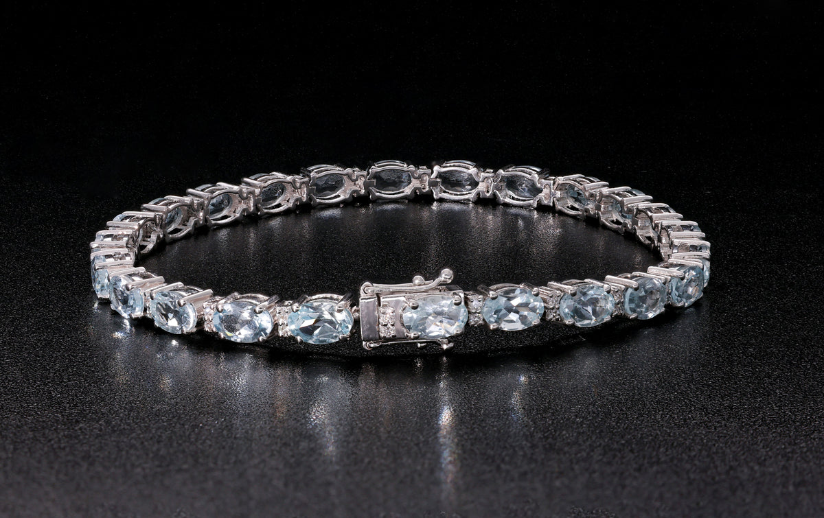 Aquamarine tennis bracelet in 18K white gold featuring oval blue aquamarine gemstones and sparkling diamond accents.