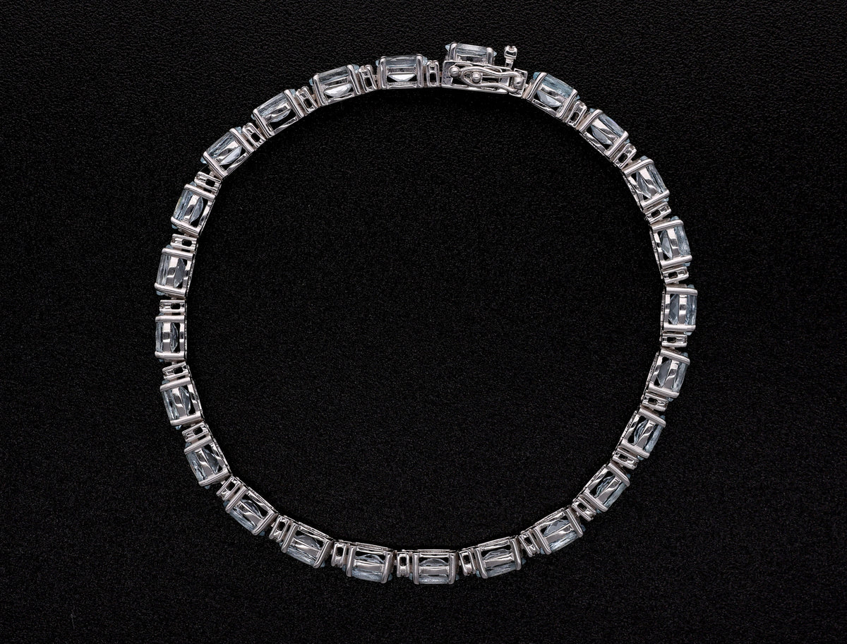 Aquamarine tennis bracelet in 18K white gold featuring oval blue aquamarine gemstones and sparkling diamond accents.