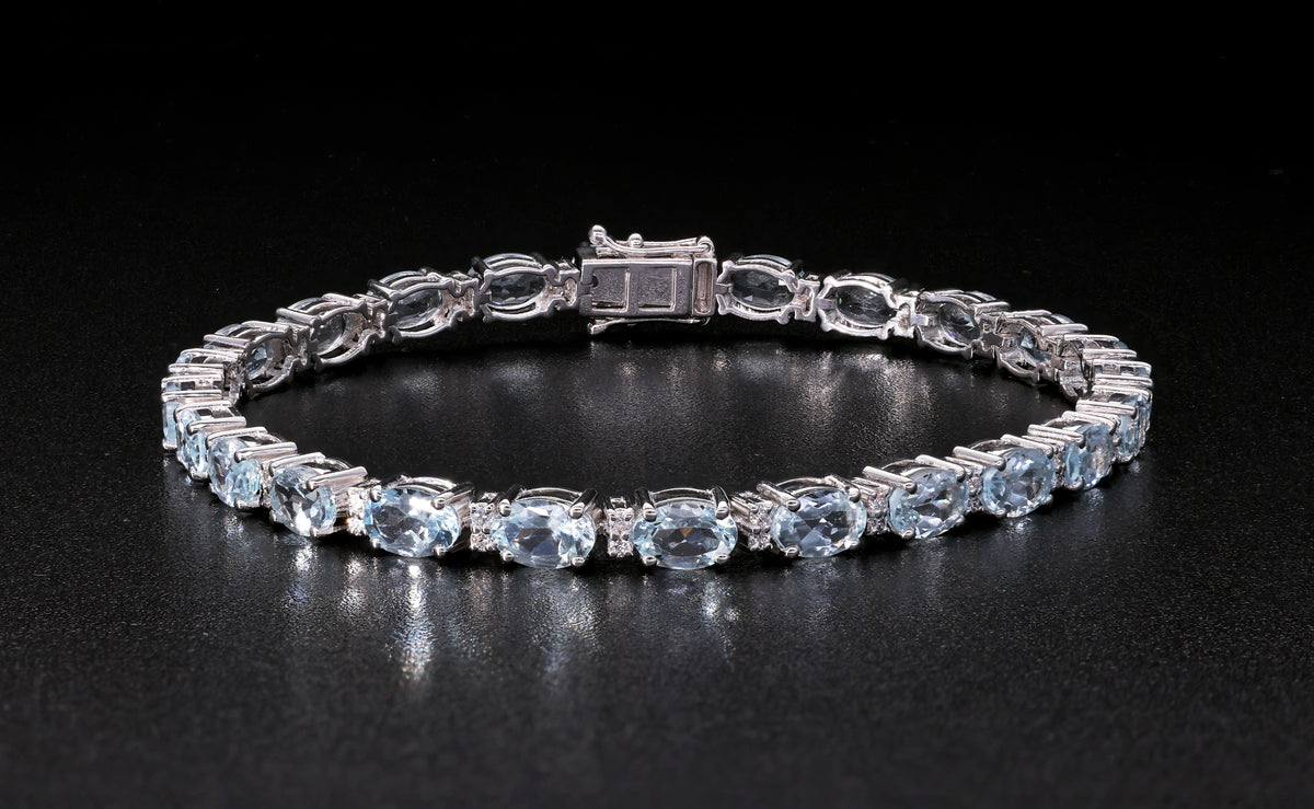 Aquamarine tennis bracelet in 18K white gold featuring oval blue aquamarine gemstones and sparkling diamond accents.