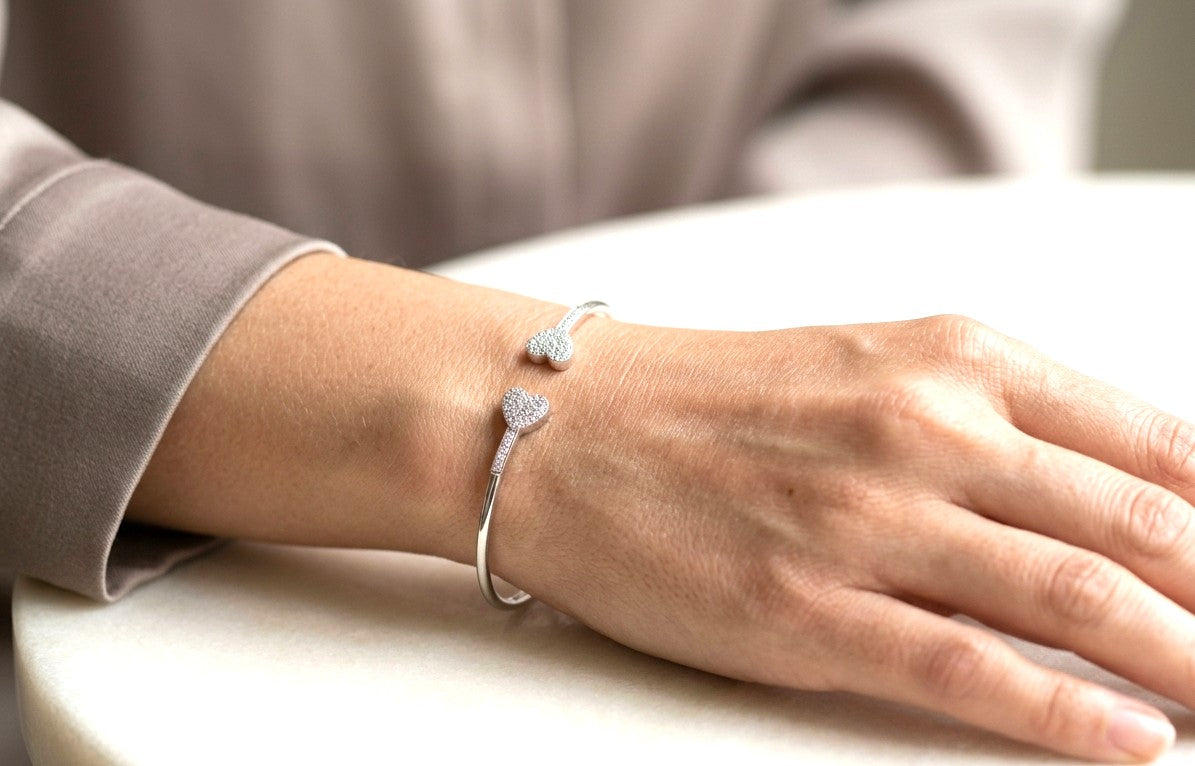 18K white gold open diamond bangle featuring two opposing heart motifs with round brilliant diamonds