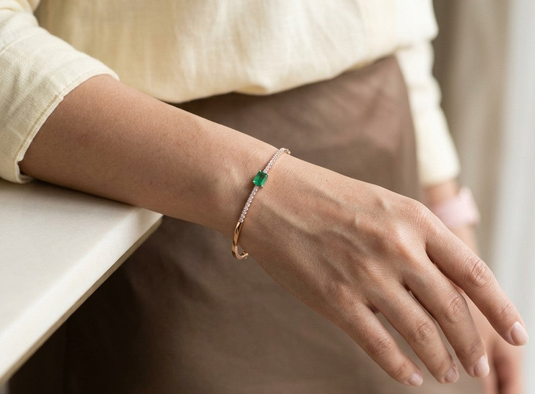 18K rose gold emerald and diamond bangle with emerald-cut green emerald and round diamond shoulders