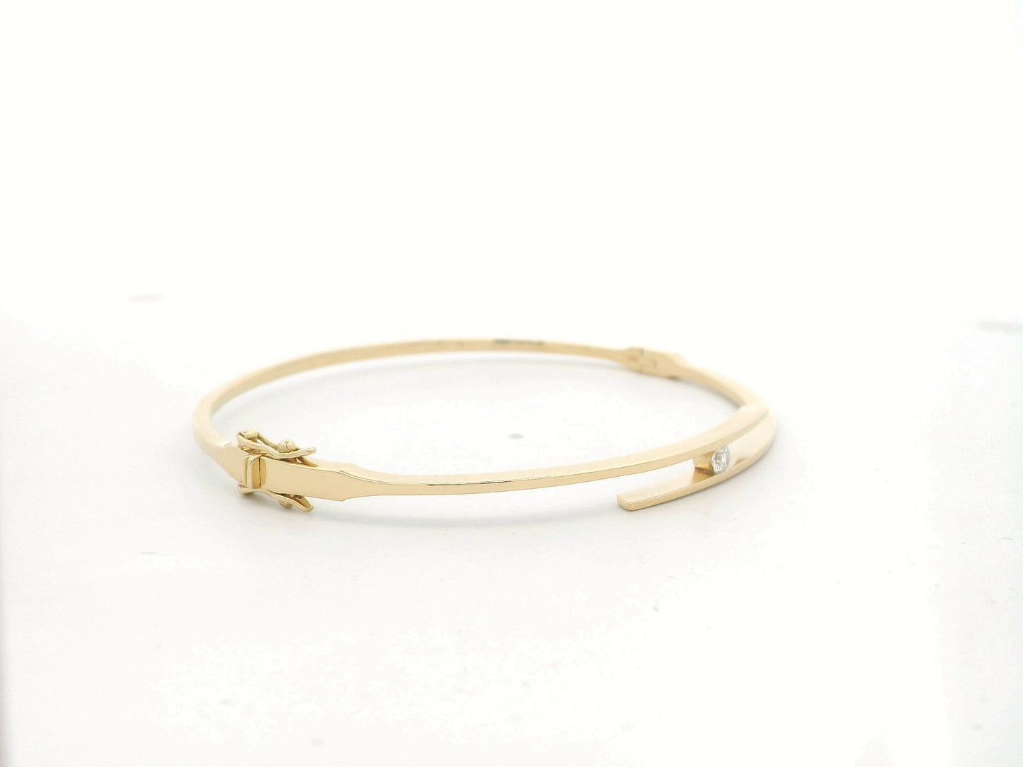18K yellow gold rigid open bangle with tension-set 0.10 carat diamond by Emirates Diamonds