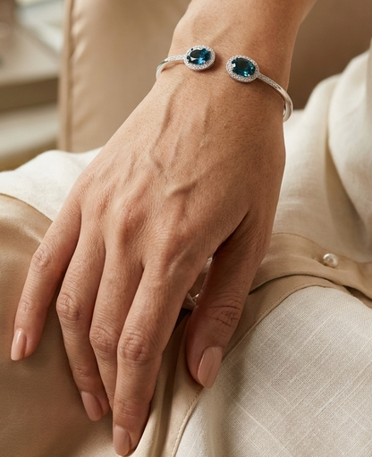18K white gold open cuff bangle featuring two oval natural London Blue Topaz gemstones totaling 4.21 carats, surrounded by natural diamond halos totaling 0.57 carat.
