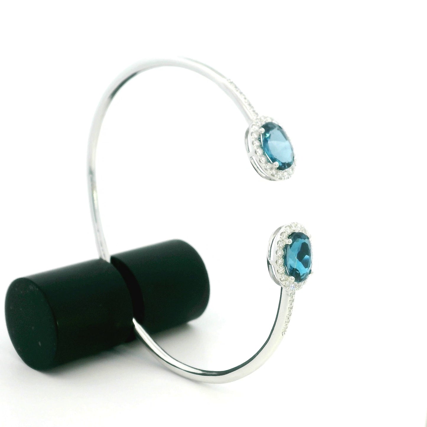 18K white gold open cuff bangle featuring two oval natural London Blue Topaz gemstones totaling 4.21 carats, surrounded by natural diamond halos totaling 0.57 carat.