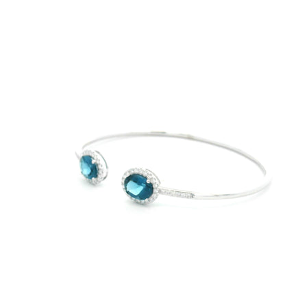 18K white gold open cuff bangle featuring two oval natural London Blue Topaz gemstones totaling 4.21 carats, surrounded by natural diamond halos totaling 0.57 carat.