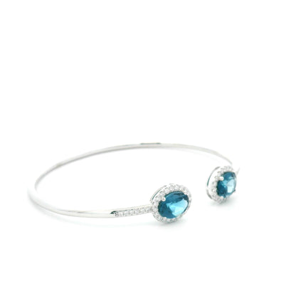 18K white gold open cuff bangle featuring two oval natural London Blue Topaz gemstones totaling 4.21 carats, surrounded by natural diamond halos totaling 0.57 carat.