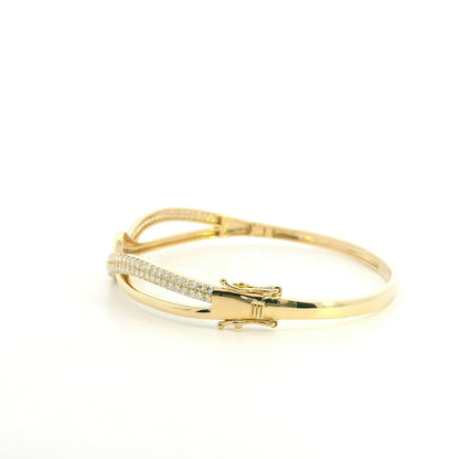 18K yellow gold diamond crossover bangle with intertwined polished and pavé diamond-set sections.