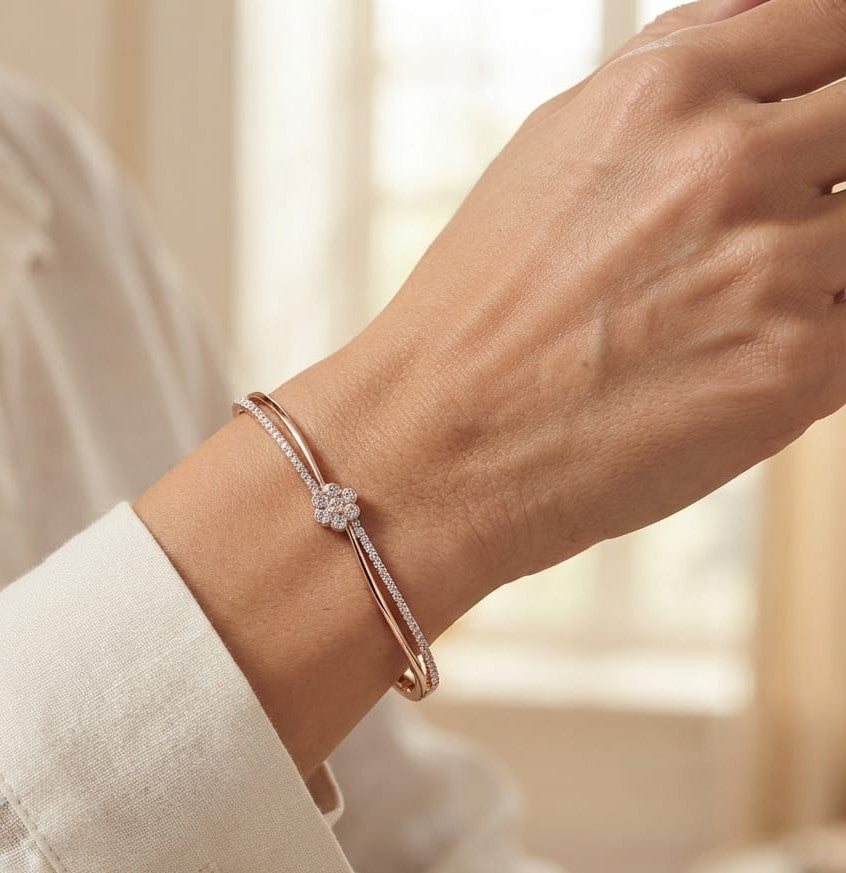 18K rose gold double row diamond bangle with flowing wave design, pavé diamond detailing and central floral diamond motif.