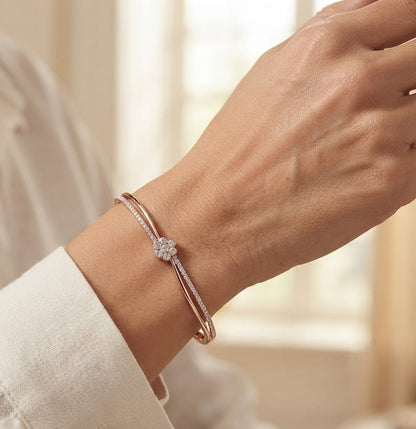18K rose gold double row diamond bangle with flowing wave design, pavé diamond detailing and central floral diamond motif.