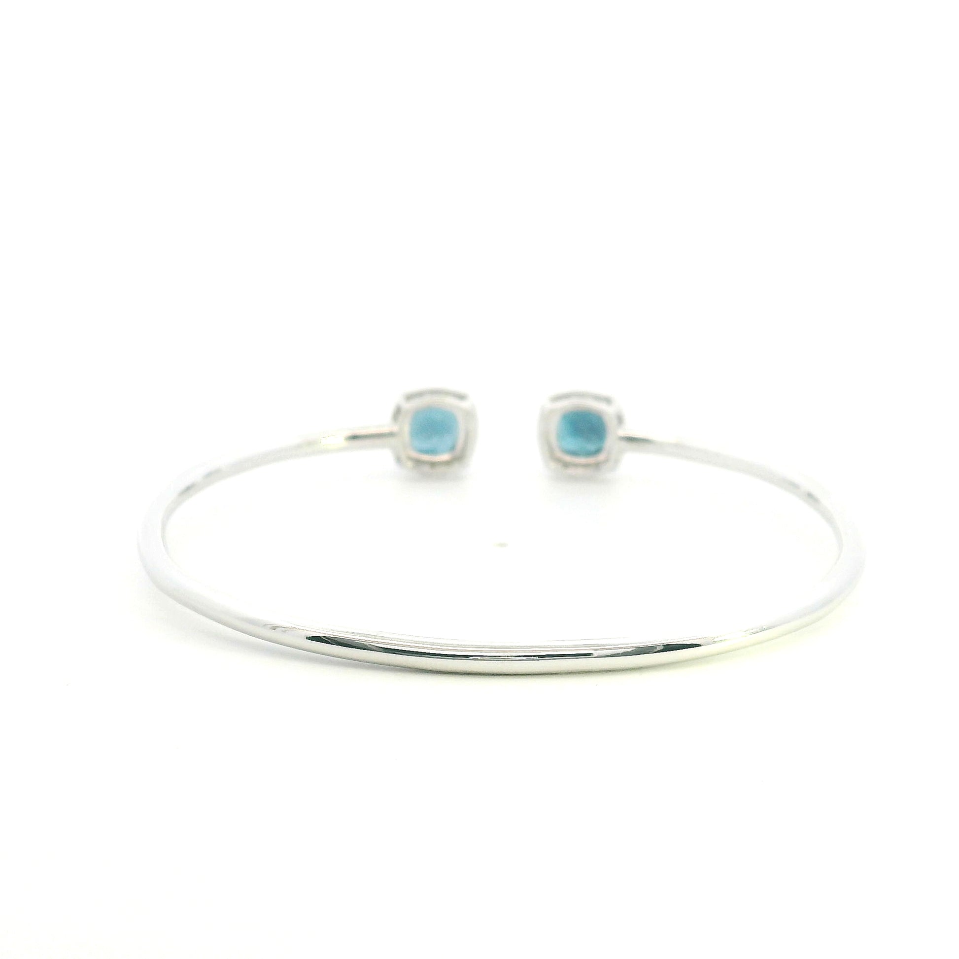 London Blue Topaz and diamond open bangle in 18K white gold with two cushion-cut blue topaz gemstones and diamond surrounds