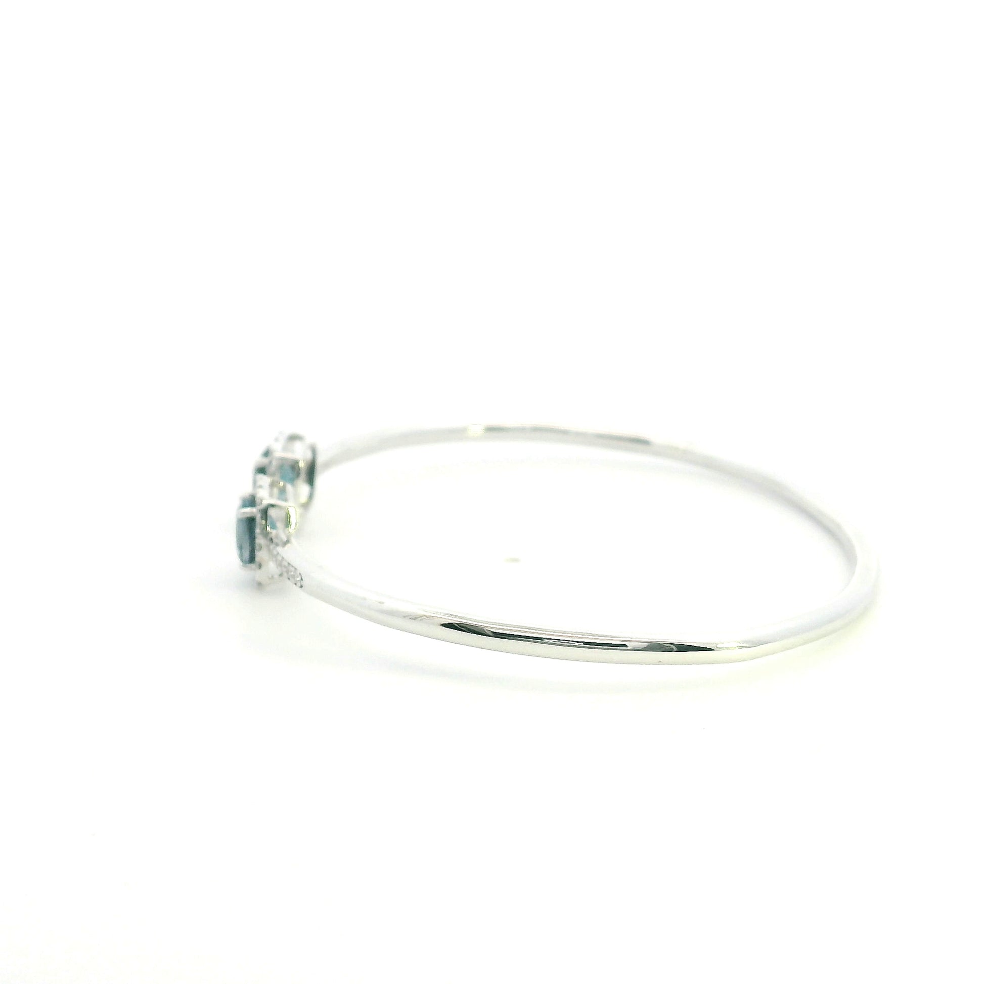 London Blue Topaz and diamond open bangle in 18K white gold with two cushion-cut blue topaz gemstones and diamond surrounds