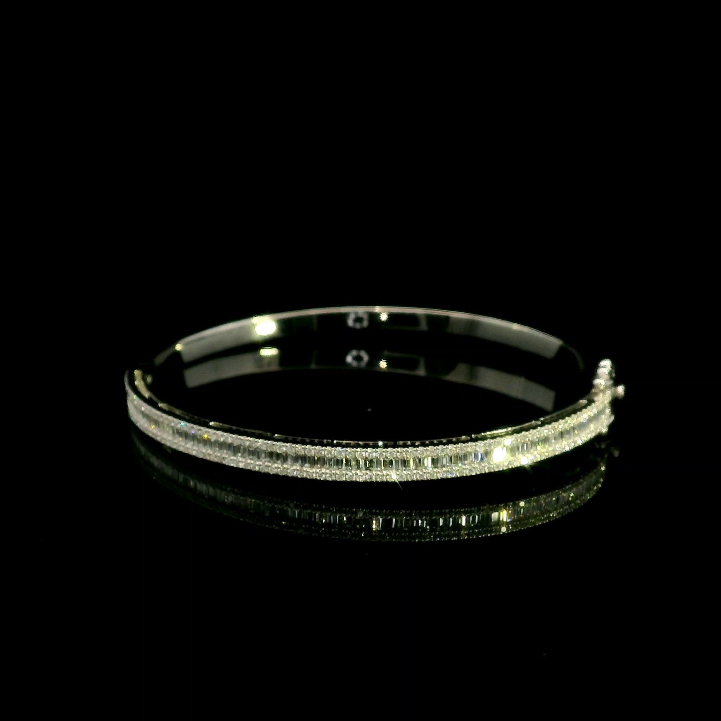 18K white gold diamond bangle with a central row of baguette diamonds framed by round brilliant diamonds and secure hinged clasp