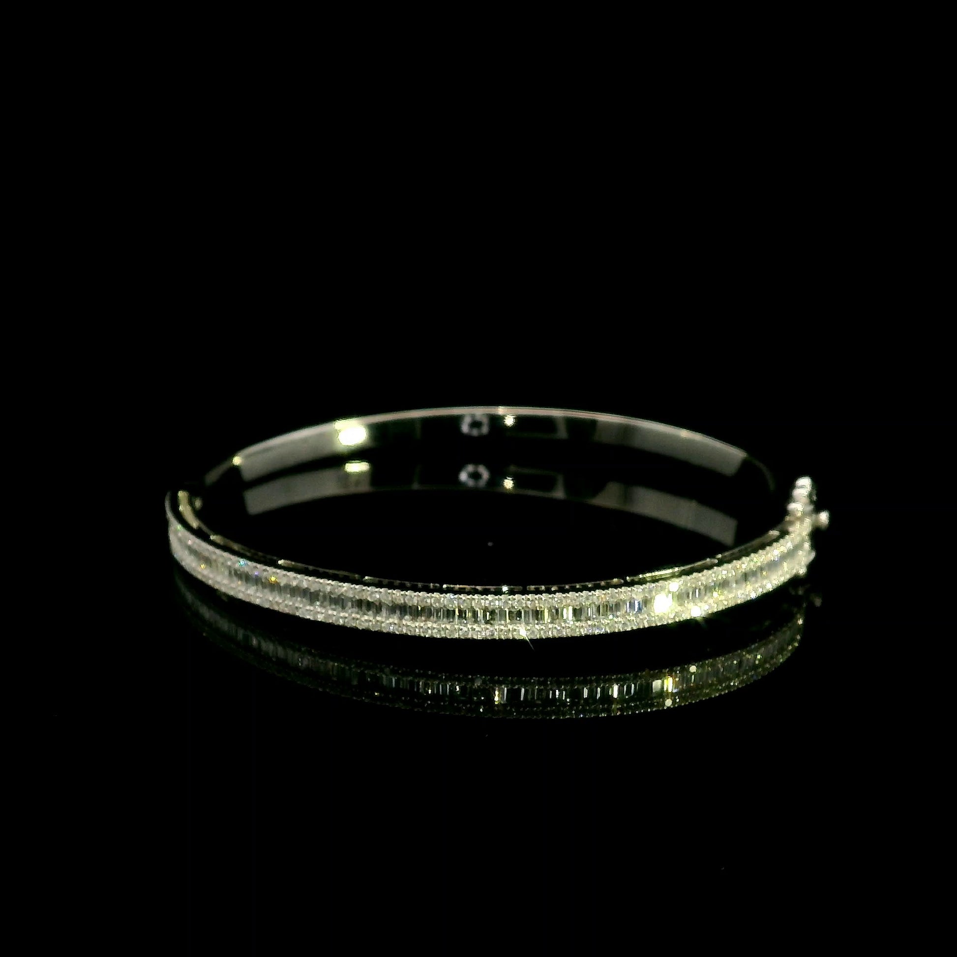 18K white gold diamond bangle with a central row of baguette diamonds framed by round brilliant diamonds and secure hinged clasp